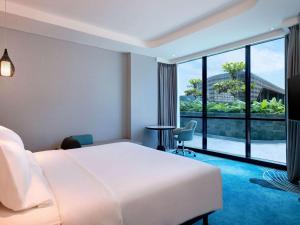 a hotel room with a bed and a large window at Novotel Yogyakarta International Airport Kulon Progo in Yogyakarta