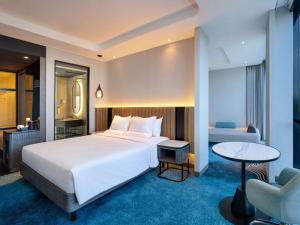 a hotel room with a large bed and a table at Novotel Yogyakarta International Airport Kulon Progo in Yogyakarta