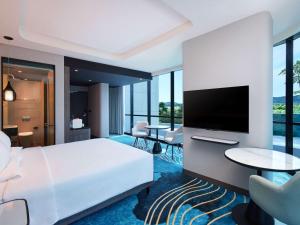 a bedroom with a large white bed and a flat screen tv at Novotel Yogyakarta International Airport Kulon Progo in Yogyakarta