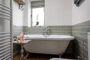 a bath tub in a bathroom with green tiles at The Bolt Hole, Winchcombe, Charming Dog-Friendly Cottage in Winchcombe +11 photos