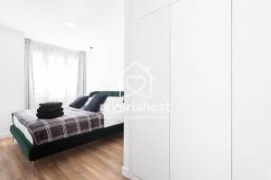 a bedroom with a bed with white walls and wooden floors at The Luxe Santa Cruz, by Nivariahost in Santa Cruz de Tenerife