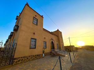 a building with the sun setting behind it at Dar Hassan Merzouga in Merzouga