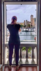 a woman looking out of a window at a marina at Vista sulla marina, AC, ascensore in Savona