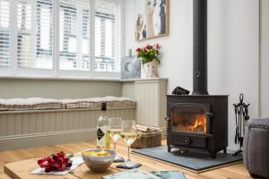 a living room with a fireplace and a table with wine glasses at The Bolt Hole, Winchcombe, Charming Dog-Friendly Cottage in Winchcombe