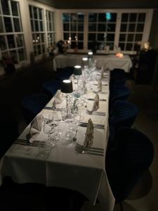 a long white table with wine glasses and blue chairs at Hotel Montagne in Åmmeberg