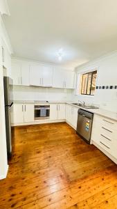 uma cozinha com armários brancos e piso em madeira em Quiet family Townhouse in Wollongong CBD em Wollongong