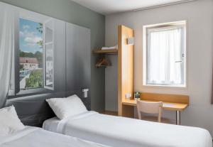 a room with two beds and a desk and a window at B&B HOTEL Troyes Saint-Parres-aux-Tertres in Saint-Parres-aux-Tertres