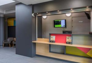 a reception desk with a tv on a wall at B&B HOTEL Troyes Saint-Parres-aux-Tertres in Saint-Parres-aux-Tertres