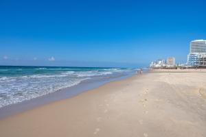 plaża z ludźmi chodzącymi po piasku i oceanie w obiekcie Hi-Yam SeaView Apartments & Suites - יש ממ"ד w mieście Bat Jam