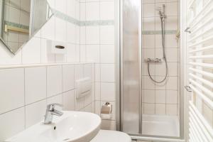 a white bathroom with a sink and a shower at Hanse Appartments II Warnemünde mit Parkplatz in Warnemünde +17 photos