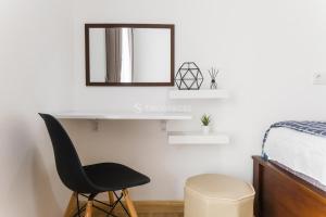 a bedroom with a chair and a mirror and a bed at Nala by TwoSpaces 2BR at Skyhouse Apartment in Tangerang +12 photos