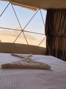 a bed in a tent with a view of the desert at wadi rum Milky Way Camp in Disah