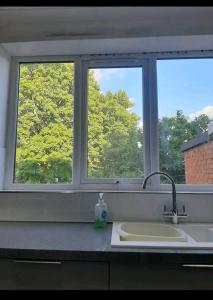 a kitchen counter with a sink and two windows at Wingfield House 3 Bed in Greasbrough