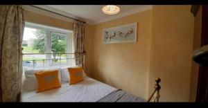 a bedroom with a bed with orange pillows and a window at Wingfield House 3 Bed in Greasbrough
