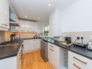 una cocina con armarios blancos y encimeras negras en High Spec Modern Flat - Reading Centre - Free allocated Parking, en Reading