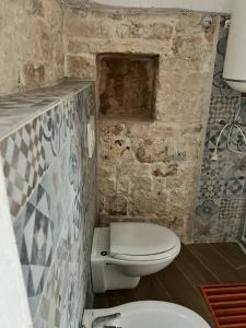 a bathroom with a toilet and a stone wall at Trullo Sofia in Monopoli