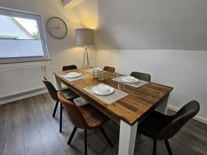 a dining room table with chairs and a clock on the wall at Ferienwohnung zur Grenze in Gronau