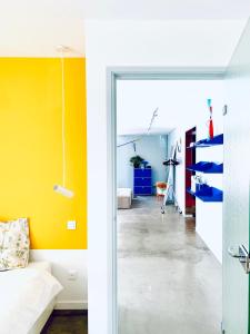 un salon avec un mur d'accent jaune et une porte coulissante en verre dans l'établissement CHAMBRE ARTY CHEZ MINUIT DEUX, à Mâcon