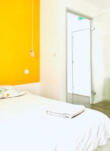 a white bed in a room with a yellow wall at CHAMBRE ARTY CHEZ MINUIT DEUX in Mâcon