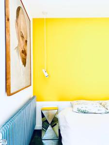 a bedroom with a bed and a yellow wall at CHAMBRE ARTY CHEZ MINUIT DEUX in Mâcon