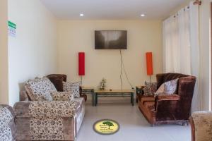 uma sala de estar com dois sofás e uma televisão em Juniper Green Gardens Resort. em Mweiga