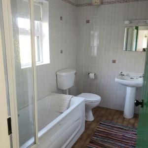 a bathroom with a tub and a toilet and a sink at Louisburgh Cottages in Louisburgh