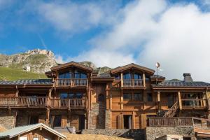 een groot houten huis met een berg op de achtergrond bij Chalet Ambre in Tignes