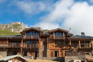 a large wooden house with a mountain in the background at Chalet Ambre in Tignes