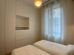- une chambre blanche avec un lit et une fenêtre dans l'établissement Appartement Monaco La Turbie avec Parking, à La Turbie