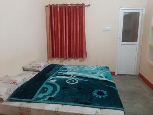 a bedroom with a bed with a blue blanket on it at Hotel Vaidehi in Varanasi