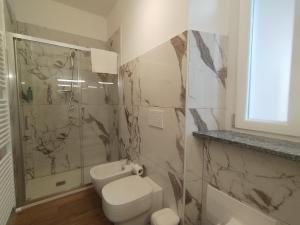 a bathroom with a toilet and a glass shower at HH Hermoso Housing Asti in Asti