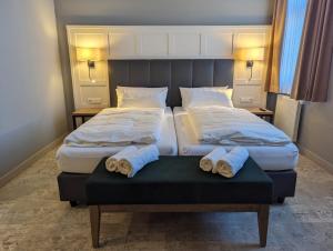 two beds in a hotel room with towels on a bench at Hotel Fürstenhof in Büdingen