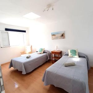Habitación blanca con 2 camas y mesa en Mirador del muelle house en Orzola
