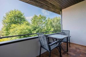 una mesa y una silla en un balcón con vistas a los árboles en Ferienwohnpark Immenstaad am Bodensee Ein-Zimmer-Apartment 49 31, en Immenstaad am Bodensee