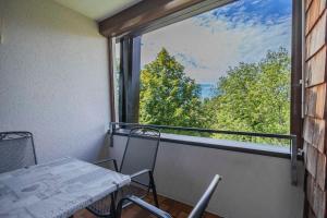 balcón con mesa, sillas y ventana en Ferienwohnpark Immenstaad am Bodensee Zwei-Zimmer-Apartment 49 47, en Immenstaad am Bodensee