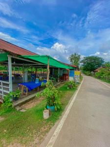 a building with a green canopy next to a road at Souksanh Guesthouse in Ban Donsôm