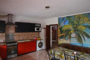 a kitchen with red cabinets and a palm tree painting on the wall at Aeropuerto Ezeiza 10 minutos de Aeropuerto in Monte Grande