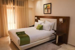 Appart-hotel Marrakech Inn في مراكش: غرفة نوم بسرير ابيض كبير مع مخدات خضراء