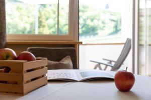 um livro aberto sobre uma mesa com maçãs e uma caixa de madeira em Hotel Burggräflerhof em Merano