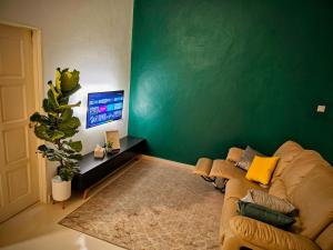 sala de estar con sofá y pared verde en Homestay Rumah Tengok Jelawat Bachok, en Bachok