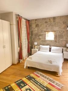 a bedroom with a white bed and a stone wall at MaSaLa Otel in Alacati