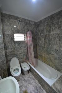 a bathroom with a toilet and a tub and a sink at Hostel Aeropuerto Ezeiza in Monte Grande