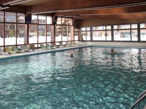 a swimming pool with two people in the water at Studio Dixence 219 by Interhome in Les Collons