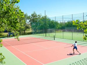 a man playing tennis on a tennis court at Holiday Home Rosapineta Camping Village-3 by Interhome in Rosapineta