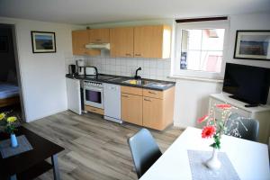 una cucina con armadi in legno e un tavolo con televisore di Meutzner Hohendorf Wolgast a Hohendorf Altre 3 foto