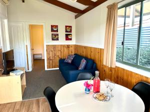 un soggiorno con tavolo e divano blu di Selwyn Cottages a Tumbarumba