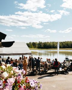 uma multidão de pessoas sentadas em mesas perto de um lago em Aurora Igloo Porvoo em Porvoo
