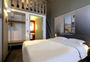 a bedroom with a large white bed and a staircase at B&B HOTEL La Rochelle Angoulins in Angoulins-sur-Mer