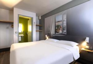 a bedroom with a large white bed and a window at B&B HOTEL La Rochelle Angoulins in Angoulins-sur-Mer