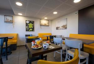 a dining room with tables and chairs with a plate of food at B&B HOTEL La Rochelle Angoulins in Angoulins-sur-Mer